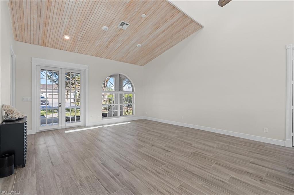 132 Wilderness Cay Naples, FL 34114 - Photo 6 of 24 an empty room with wooden floor and windows