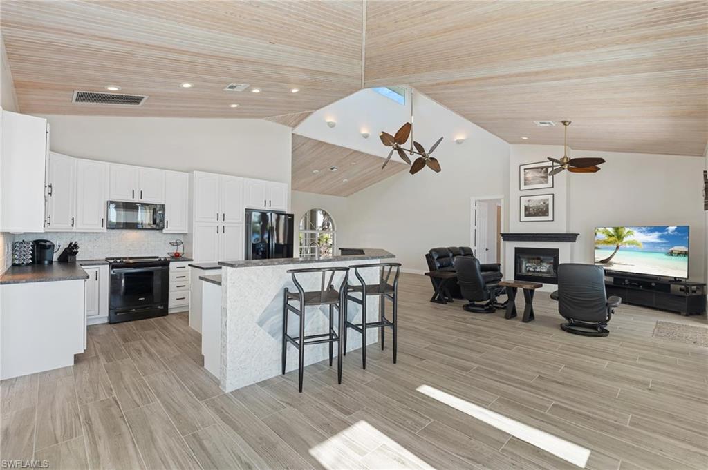 132 Wilderness Cay Naples, FL 34114 - Photo 8 of 24 a living room with furniture a fireplace and kitchen view