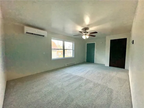an empty room with a chandelier fan and windows