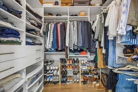 a view of walk in closet with clothes and shoes