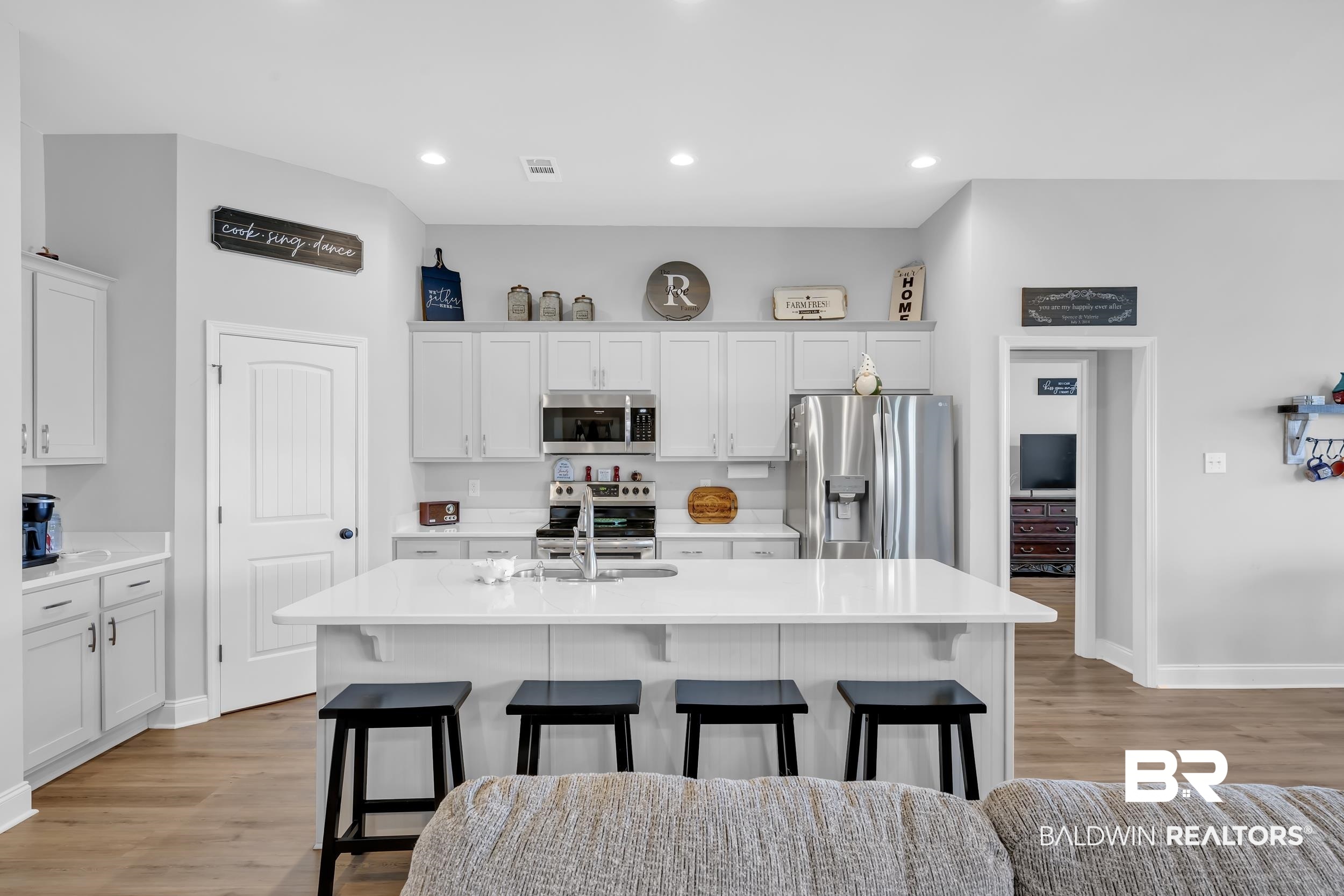 1176 Stella Road Foley, AL 36535 - Photo 11 of 40 Kitchen featuring stainless steel appliances, a kitchen breakfast bar, light wood-type flooring, white cabinetry, and a kitchen island with sink