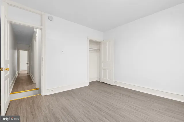 an empty room with wooden floor and a bathroom