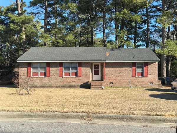 a front view of a house with a yard covered with snow and trees