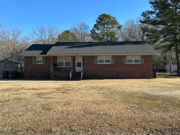 a front view of house with yard and trees in the background