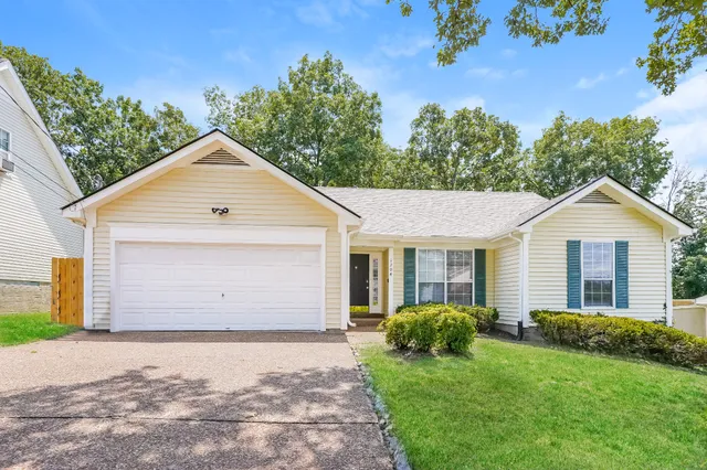 a front view of house with yard and trees in the background