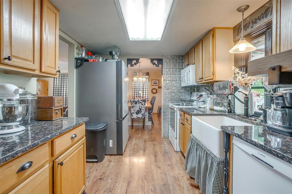 8716 County Road 1224A Rio Vista, TX 76093 - Photo 27 of 38 Kitchen featuring white appliances, decorative light fixtures, light wood finished floors, and dark stone countertops