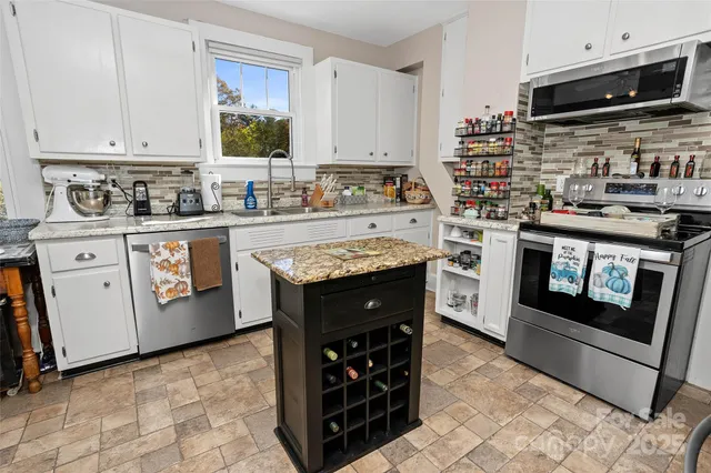 a kitchen with stainless steel appliances granite countertop a stove a sink and a microwave