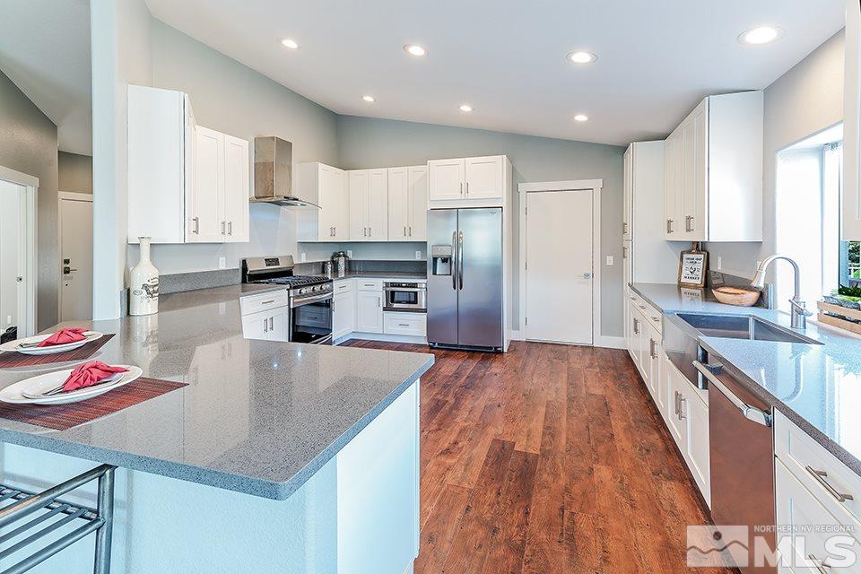 2450 Granite Springs Road Reno, NV 89519 - Photo 3 of 17 a kitchen with stainless steel appliances granite countertop a refrigerator a stove top oven a sink dishwasher and white cabinets with wooden floor