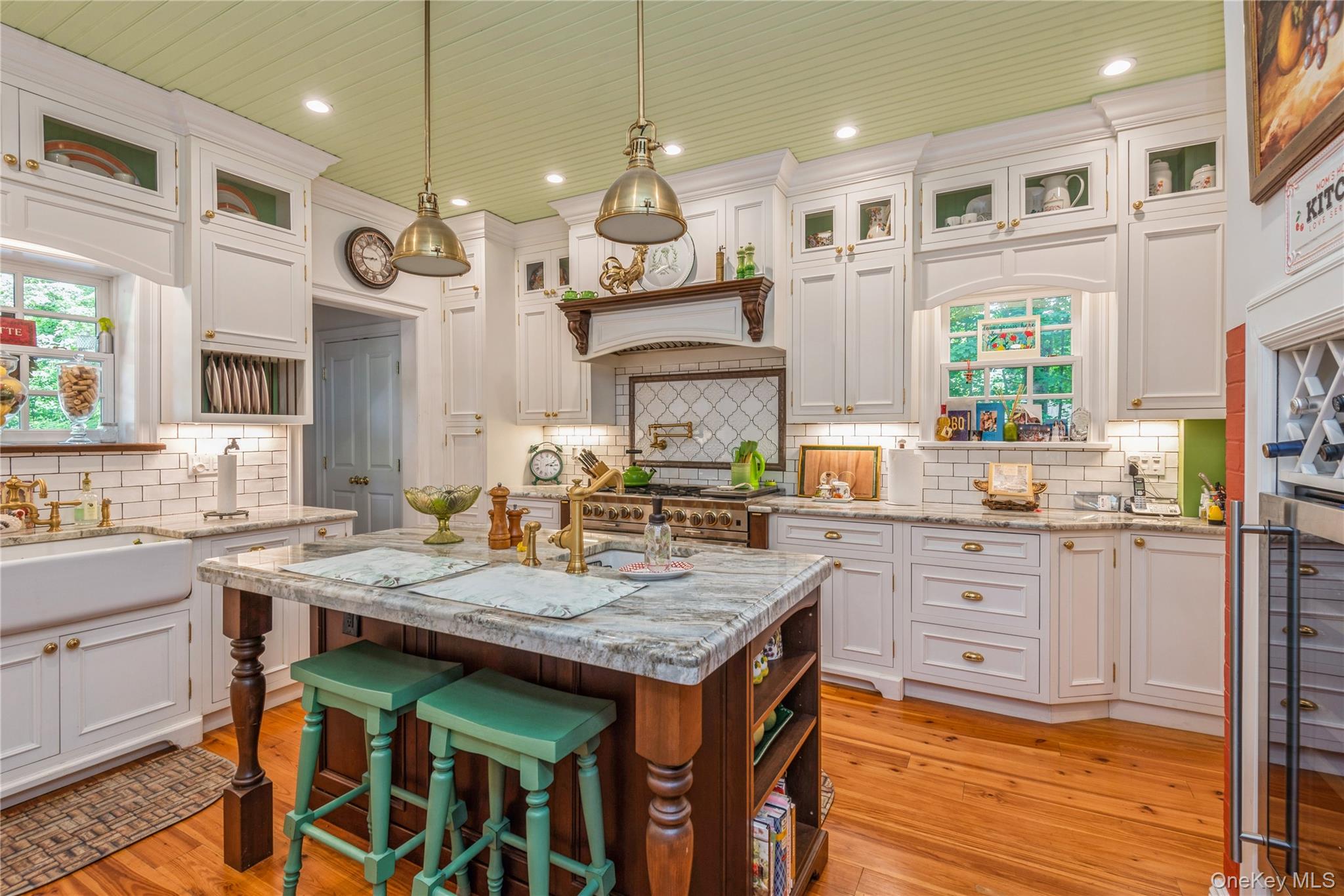110 Red Spring Lane Glen Cove, NY 11542 - Photo 21 of 43 Gourmet kitchen featuring a central island with granite countertop, white shaker cabinetry with brass hardware, subway tile backsplash, and wood-finish flooring
