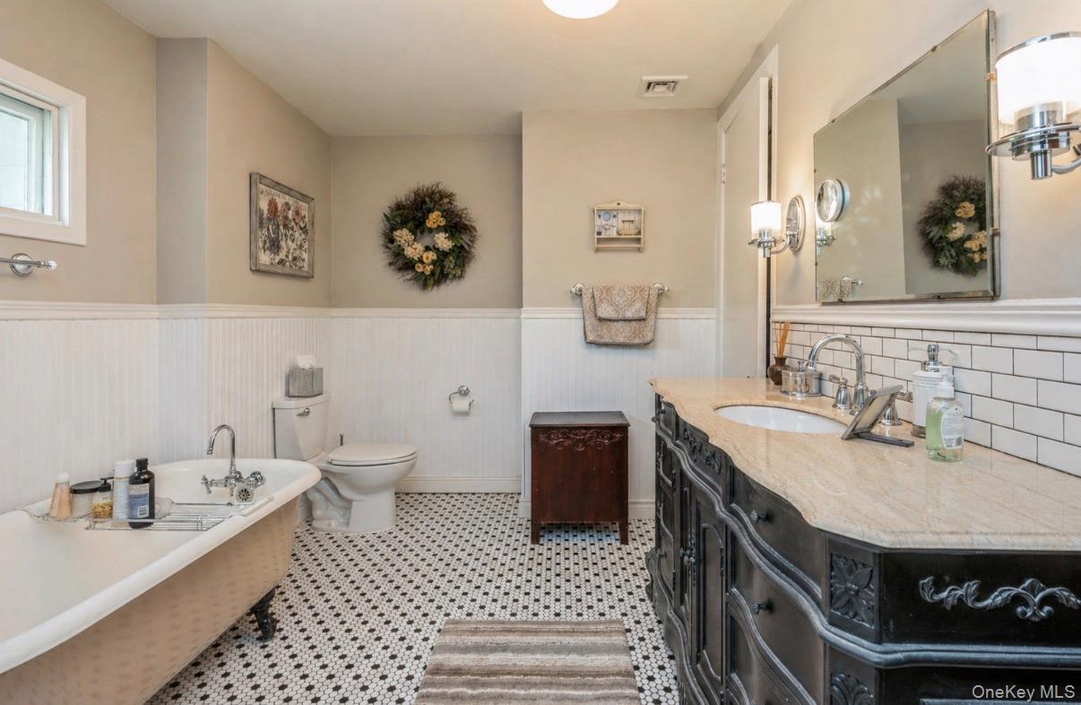 110 Red Spring Lane Glen Cove, NY 11542 - Photo 33 of 43 Bathroom featuring a clawfoot bathtub, black and white hexagonal tile flooring, a double vanity and beadboard paneling