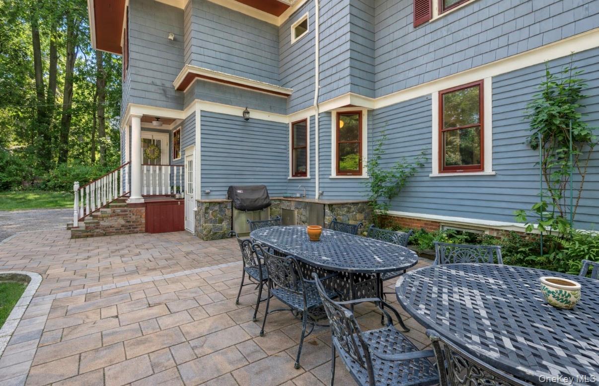 110 Red Spring Lane Glen Cove, NY 11542 - Photo 39 of 43 Expansive paver patio with a stone-clad outdoor kitchen area and a side entrance