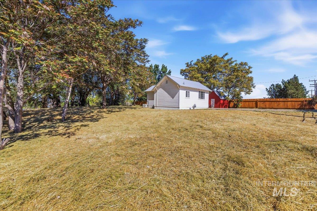 109 Parma Road Parma, ID 83660 - Photo 30 of 31 Spacious outdoor area featuring a manicured lawn, established perimeter trees, and a wooden privacy fence