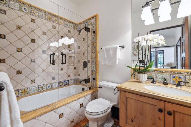 a bathroom with a granite countertop sink a mirror a vanity and a bathtub