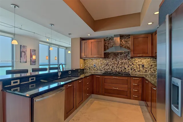 a kitchen with stainless steel appliances kitchen island granite countertop a table chairs and wooden cabinets