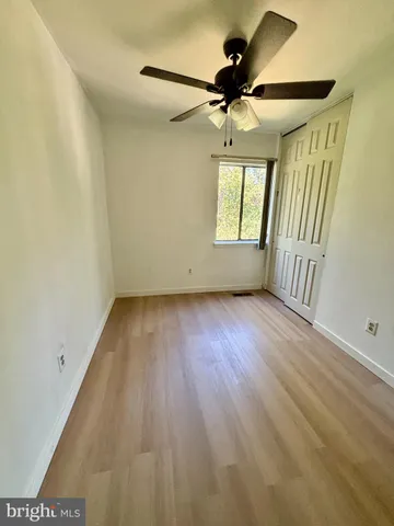 an empty room with wooden floor fan and windows