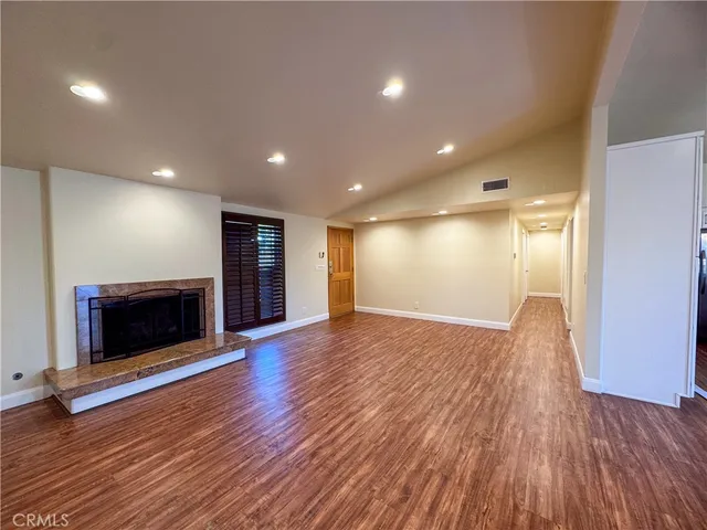 a view of empty room with wooden floor and fireplace