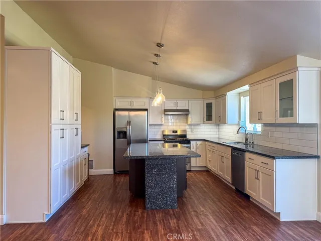 a large kitchen with a center island and wooden floor