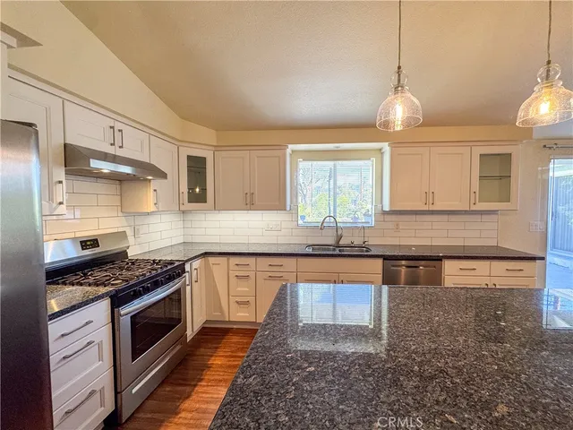 a kitchen with stainless steel appliances granite countertop a stove a sink and a refrigerator