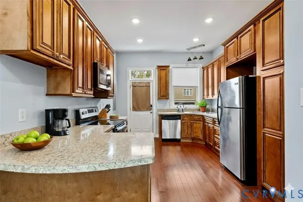 a kitchen with stainless steel appliances granite countertop a refrigerator a stove and a sink