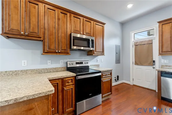 a kitchen with stainless steel appliances granite countertop a stove a sink dishwasher and a microwave oven with wooden floor