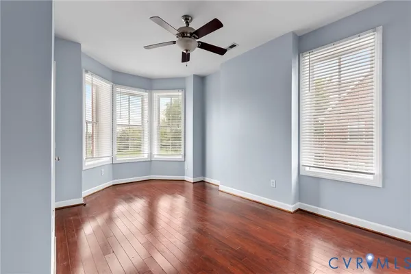 an empty room with wooden floor and windows