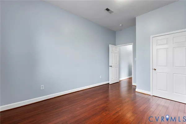 a view of an empty room with wooden floor and closet