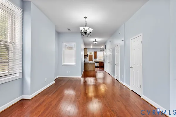 a view of a hallway with wooden floor and a kitchen