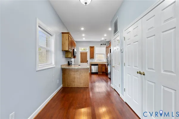 a view of a hallway with wooden floor and a kitchen