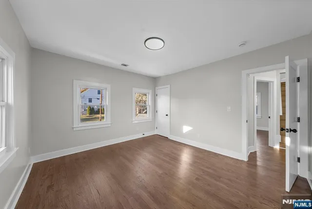 a view of a big room with wooden floor and windows