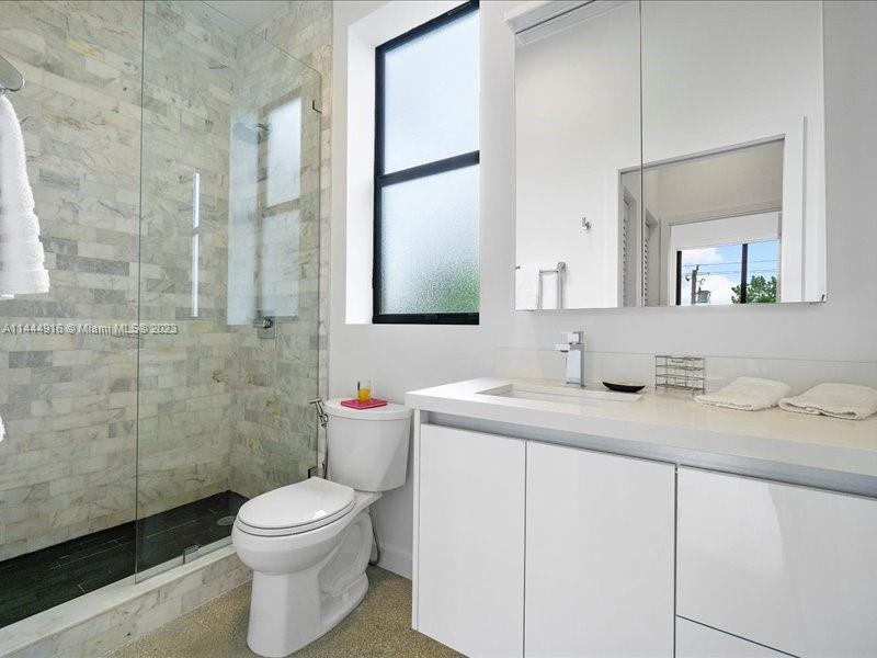 1053 Northwest 29th Street Miami, FL 33127 - Photo 21 of 38 a bathroom with a granite countertop sink a toilet and a mirror