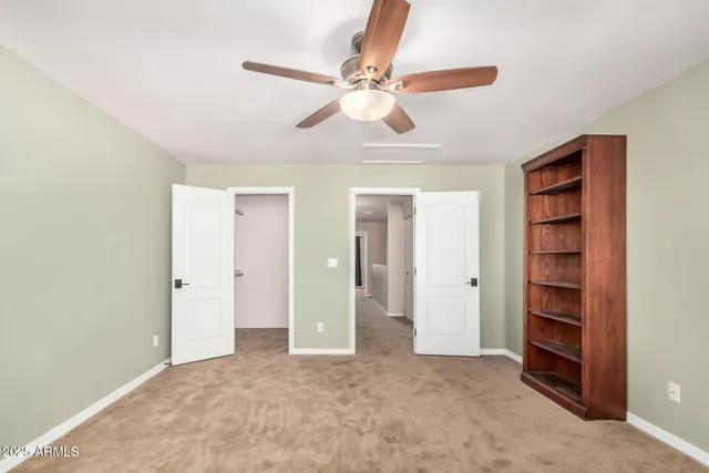 an empty room with windows and a ceiling fan