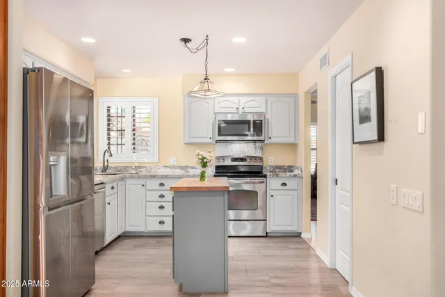 a kitchen with stainless steel appliances white cabinets a sink a stove a refrigerator and a microwave