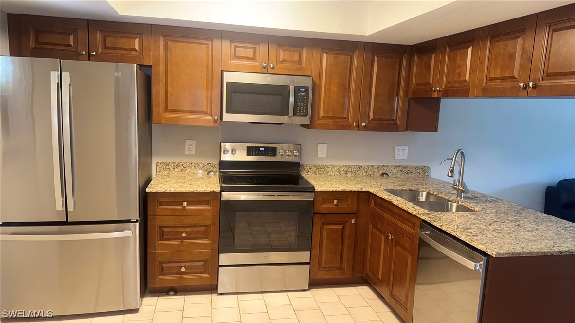 606 Gerald Avenue, Unit 115 Lehigh Acres, FL 33936 - Photo 3 of 7 a kitchen with a sink stove and refrigerator