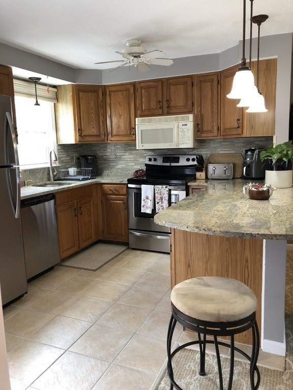 36 Atkins Road, Unit B5 Sandwich, MA 02537 - Photo 8 of 23 a kitchen with stainless steel appliances granite countertop a stove a sink a microwave a dining table and chairs