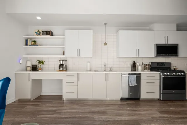 a kitchen with stainless steel appliances white cabinets and wooden floor