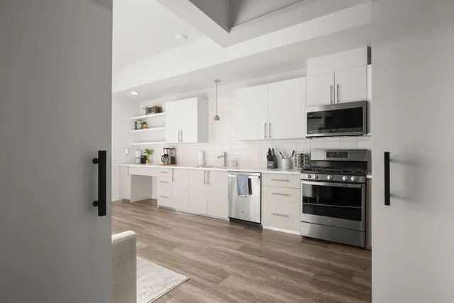 a kitchen with stainless steel appliances white cabinets a sink a stove a microwave and cabinetry