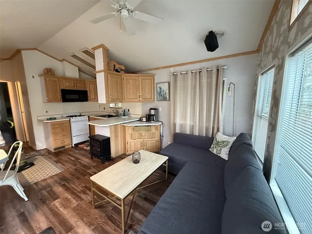a living room with stainless steel appliances furniture a flat screen tv and a window