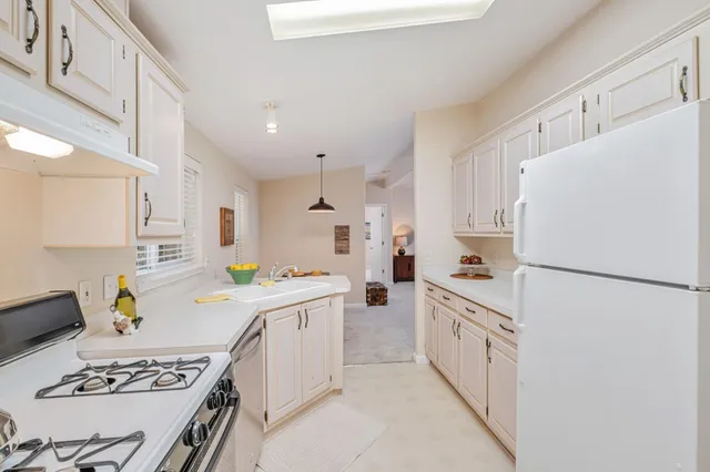 a kitchen with stainless steel appliances a refrigerator sink and white cabinets