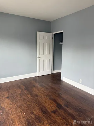 a view of an empty room with wooden floor and closet