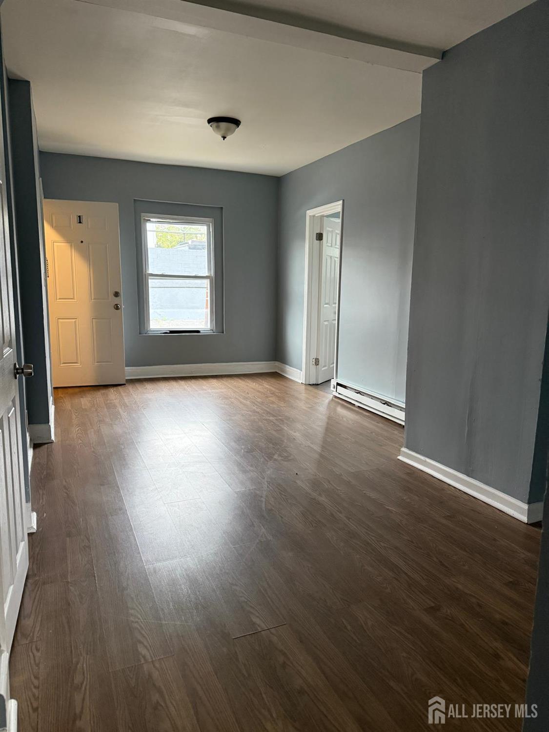 1301 South 2nd Street, Unit 1311 Plainfield, NJ 07063 - Photo 7 of 14 an empty room with wooden floor and windows