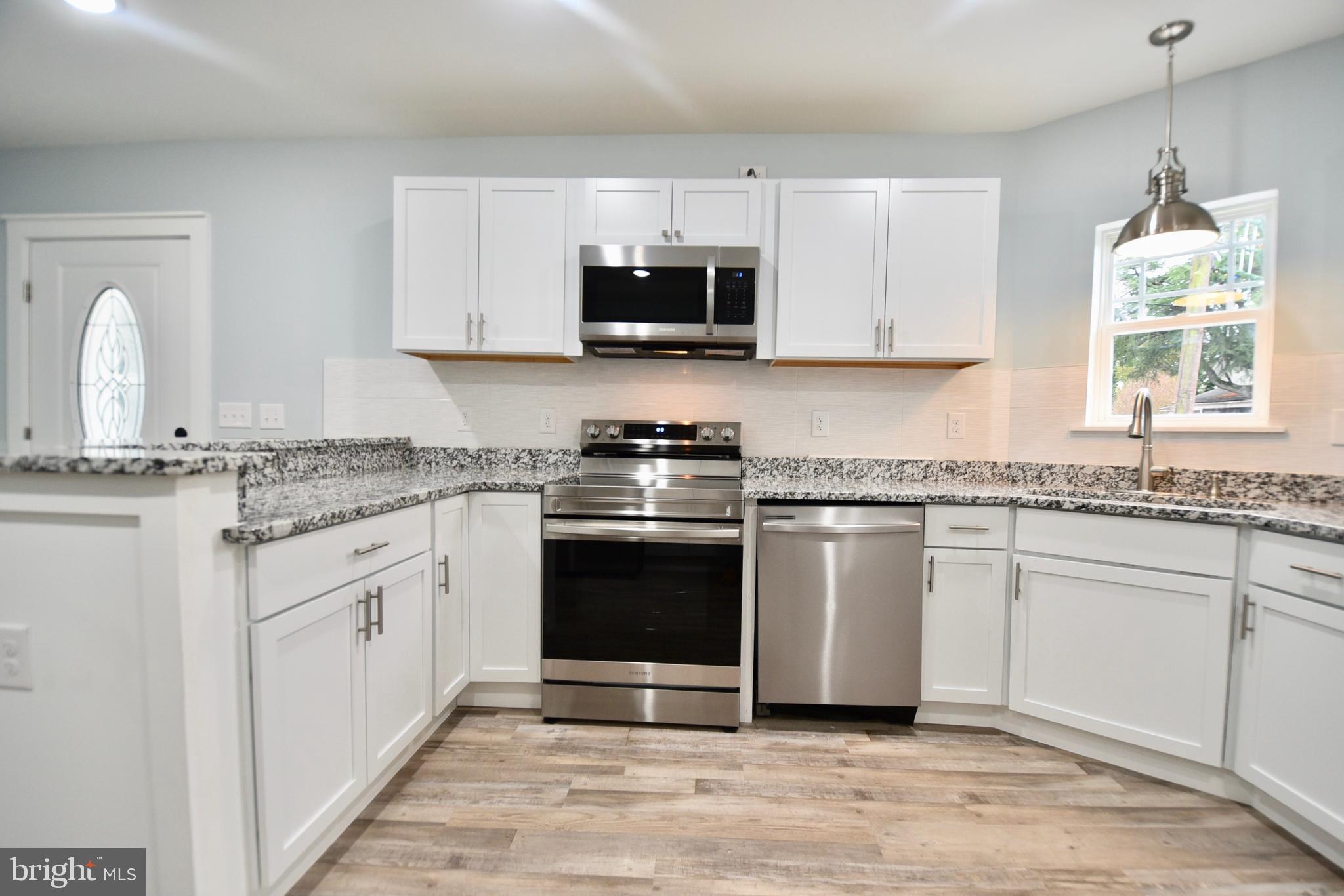 611 Main Street Sharptown, MD 21861 - Photo 4 of 37 a kitchen with granite countertop white cabinets appliances a sink and a window