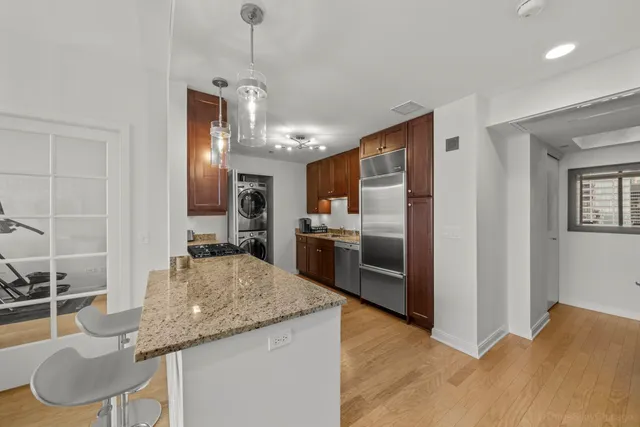 a kitchen with granite countertop kitchen island stainless steel appliances a sink stove and refrigerator