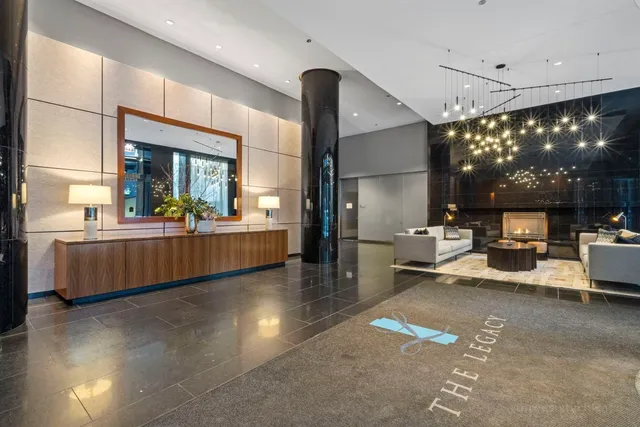 a living room with furniture a rug kitchen view and a large window