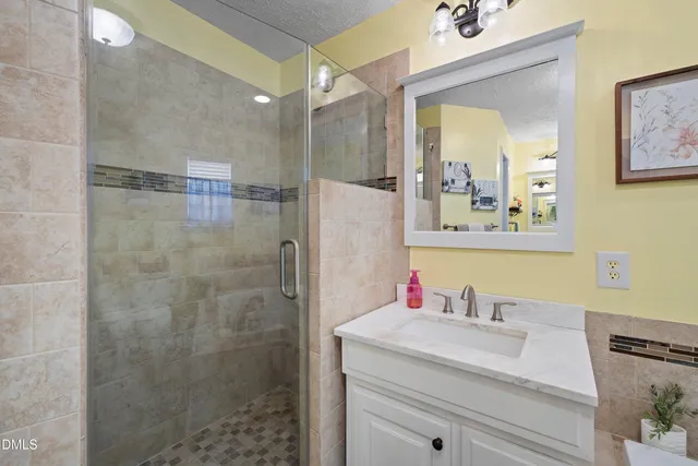 a bathroom with a granite countertop shower sink vanity and mirror