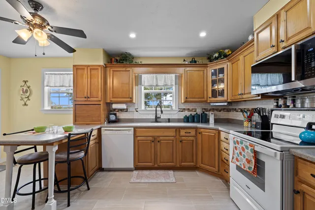 a kitchen with stainless steel appliances granite countertop a stove top oven a sink dishwasher a dining table and chairs with wooden cabinets