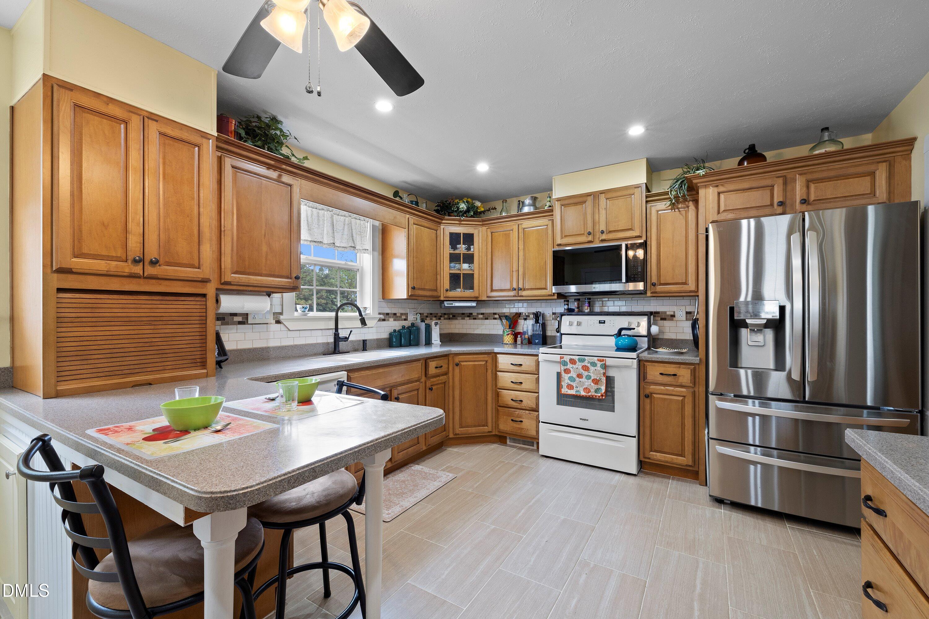 89 Bailey-Boykin Road Selma, NC 27576 - Photo 27 of 48 a kitchen with stainless steel appliances kitchen island granite countertop a refrigerator a stove top oven a sink dishwasher and white cabinets with wooden floor