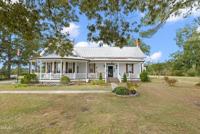 a front view of a house with garden and trees