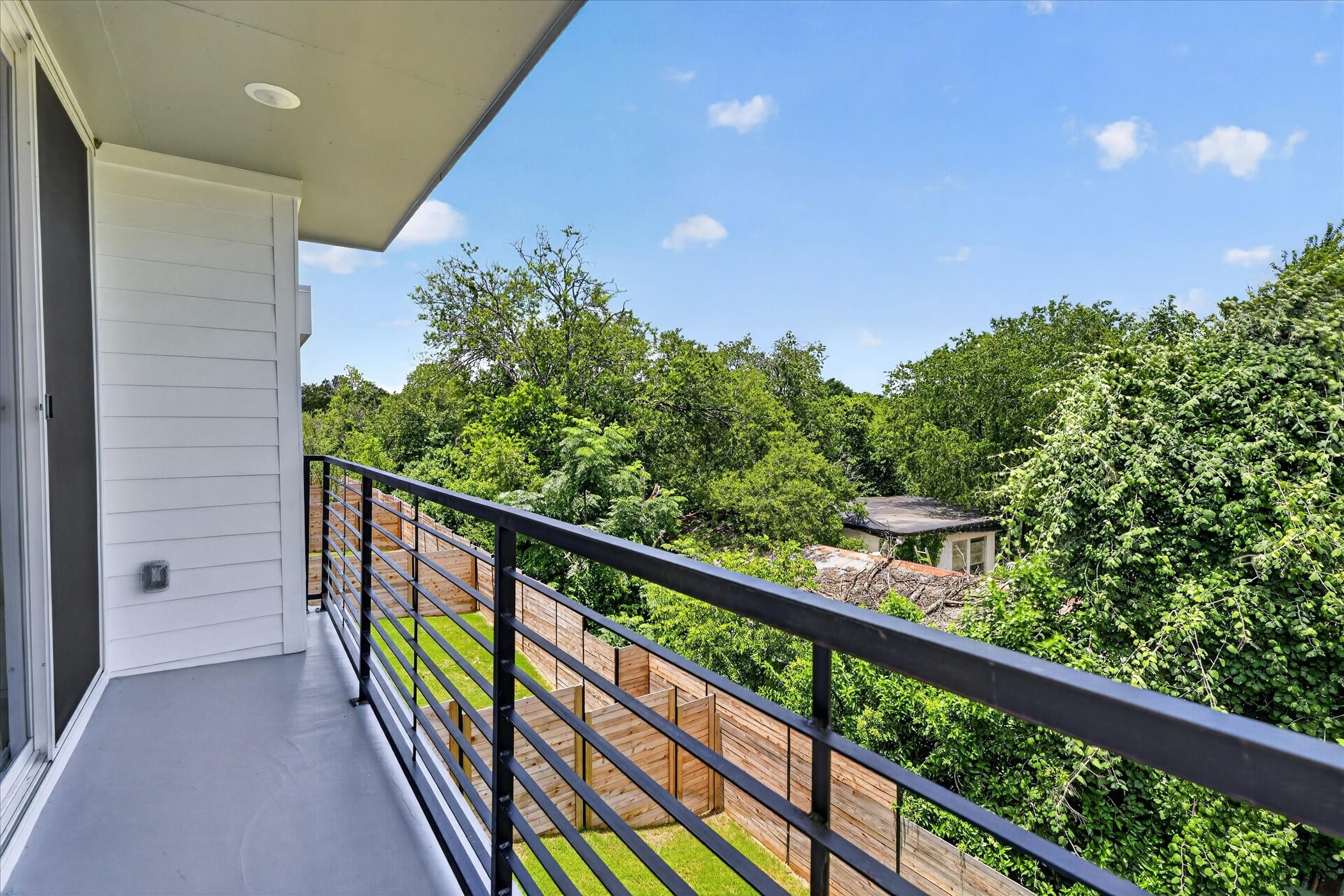 2000 Riverside Farms Road, Unit 8101 Austin, TX 78741 - Photo 18 of 41 This photo showcases a modern balcony with sleek railing, offering a serene view of lush greenery and a spacious backyard, perfect for relaxation.