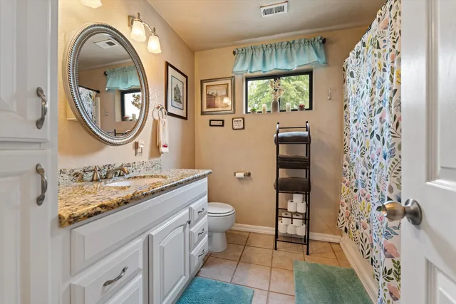 a bathroom with a granite countertop toilet a sink and a mirror