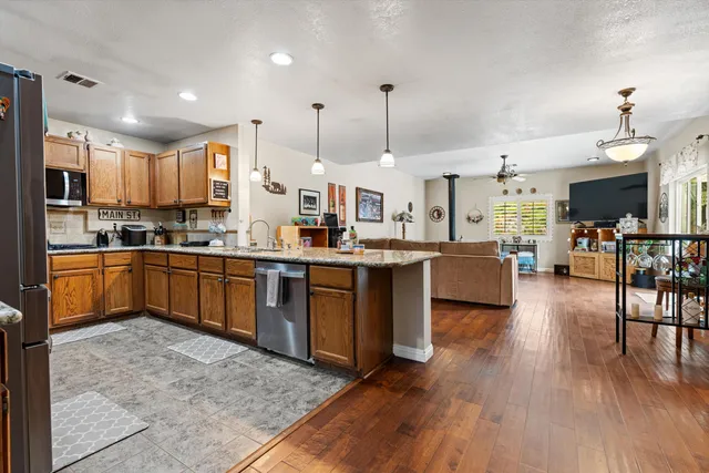 a kitchen with stainless steel appliances kitchen island granite countertop wooden floors and white cabinets